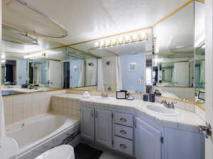 Bathroom with a shower with curtain, a bath, double vanity, and a textured ceiling