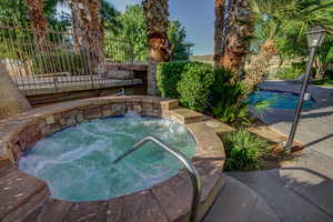 View of swimming pool with an in-ground hot tub and fence