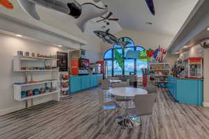 Dining area with wood finished floors, high vaulted ceiling, baseboards, and a ceiling fan
