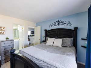Bedroom with light colored carpet and connected bathroom