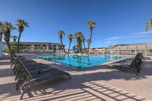 Community pool featuring a patio area and fence