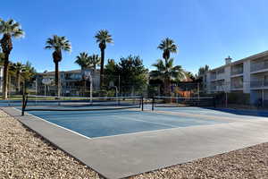 View of tennis court with fence and community basketball court