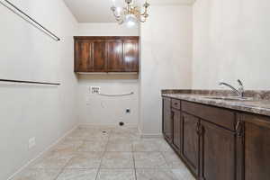 Laundry area featuring electric dryer hookup, cabinet space, hookup for a washing machine, a chandelier, and baseboards