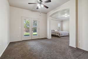 Bedroom featuring access to exterior, dark carpet, french doors, arched walkways, and a ceiling fan