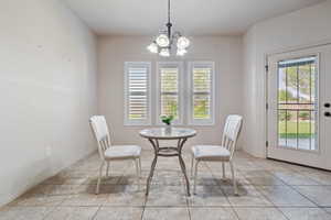 Dining room with a chandelier, light tile patterned flooring, and baseboards