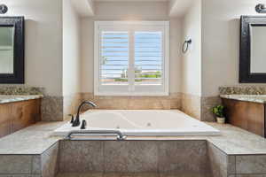 Full bath with vanity and a jetted tub