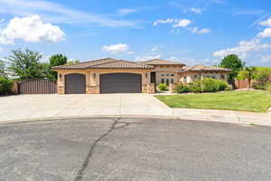 Mediterranean / spanish-style home with stucco siding, stone siding, a garage, driveway, and a tile roof