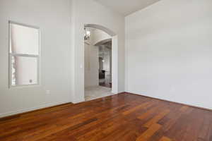 Empty room featuring arched walkways, wood finished floors, and baseboards