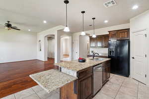 Kitchen featuring black fridge with ice dispenser, dishwasher, a sink, a ceiling fan, and arched walkways