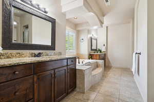 Full bathroom featuring two vanities, a garden tub, baseboards, and tile patterned flooring