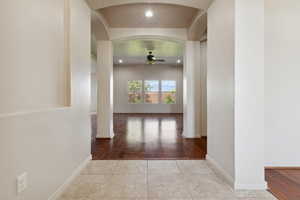 Corridor featuring arched walkways, wood finished floors, baseboards, and recessed lighting