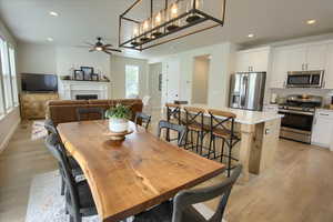 Dining space featuring ceiling fan, light wood-style floors, a fireplace, recessed lighting, and baseboards