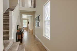 Foyer with stairs, light wood-style floors, and baseboards