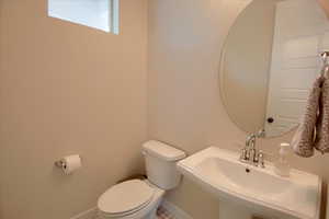 Bathroom featuring toilet, a sink, and baseboards