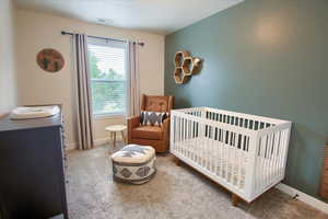 Bedroom with carpet, baseboards, and a nursery area
