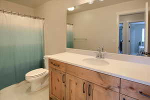 Bathroom with toilet, vanity, tile patterned flooring, and a shower with curtain