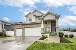 Craftsman-style home featuring stone siding, board and batten siding, driveway, covered porch, and a garage