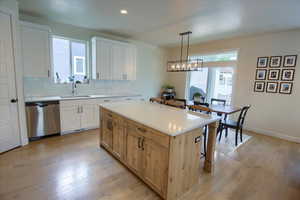 Kitchen with stainless steel dishwasher, a sink, light wood-style floors, decorative backsplash, and recessed lighting