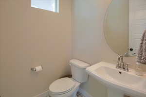 Bathroom featuring a sink, toilet, and baseboards