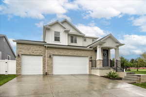 View of front of home featuring board and batten siding, stone siding, driveway, and an attached garage