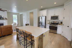 Kitchen with stainless steel appliances, open floor plan, a kitchen bar, a kitchen island, and light wood-style flooring