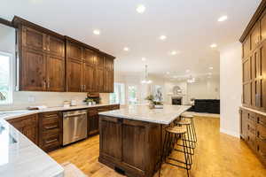 Kitchen featuring stainless steel dishwasher, recessed lighting, a center island, open floor plan, and light stone countertops