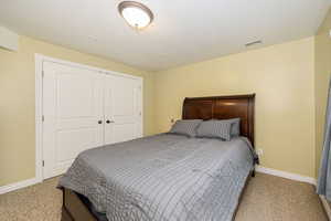 Bedroom with light colored carpet, baseboards, and a closet