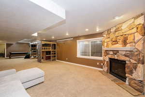 Living area with a fireplace, carpet, a textured ceiling, baseboards, and recessed lighting