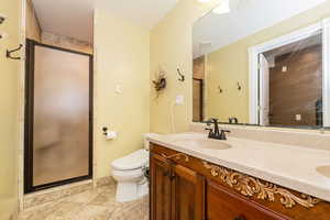 Full bath with a stall shower, toilet, and double vanity