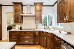 Kitchen featuring a sink, crown molding, stainless steel dishwasher, backsplash, and light wood finished floors