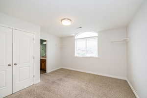 Unfurnished bedroom with light carpet, baseboards, and a closet