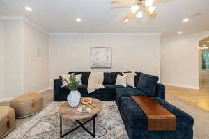 Carpeted living room featuring recessed lighting, ceiling fan, baseboards, arched walkways, and ornamental molding