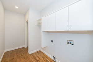 Washroom featuring hookup for an electric dryer, hookup for a washing machine, cabinet space, light wood finished floors, and baseboards
