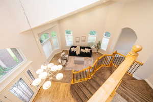 Living room with a high ceiling, healthy amount of natural light, baseboards, wood finished floors, and stairway