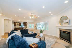 Living room featuring recessed lighting, crown molding, ceiling fan, baseboards, and a tile fireplace