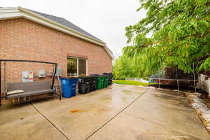 View of property exterior with a trampoline, brick siding, a patio, and fence