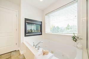 Full bath with a tub with jets and baseboards