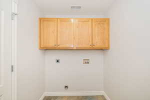 Washroom with electric dryer hookup, washer hookup, cabinet space, and baseboards