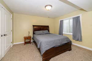 Bedroom with carpet floors, baseboards, and a textured ceiling