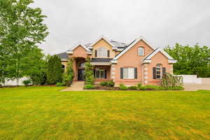Traditional-style home featuring brick siding, roof mounted solar panels, and stucco siding
