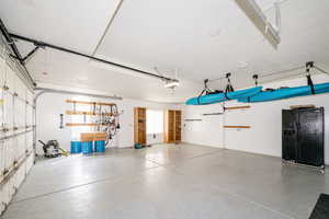 Garage featuring black fridge with ice dispenser and a garage door opener