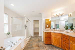 Bathroom featuring vanity, a stall shower, a bath, baseboards, and recessed lighting