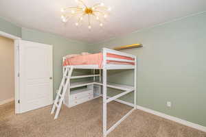 Bedroom with carpet floors, a chandelier, baseboards, and a textured ceiling