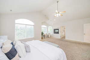 Bedroom featuring lofted ceiling, baseboards, light carpet, and a ceiling fan