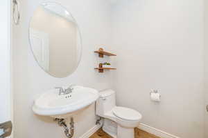 Half bathroom with wood finished floors, toilet, and baseboards