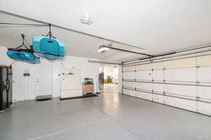 Garage featuring black fridge with ice dispenser, a garage door opener, and refrigerator