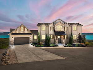 View of front facade with stone siding, board and batten siding, concrete driveway, and a garage