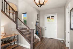 Foyer entrance featuring a chandelier, wood finished floors, and stairway