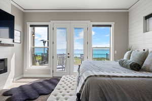 Bedroom featuring access to outside, carpet floors, crown molding, a glass covered fireplace, and wood walls