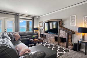 Carpeted living area featuring crown molding, french doors, and a fireplace